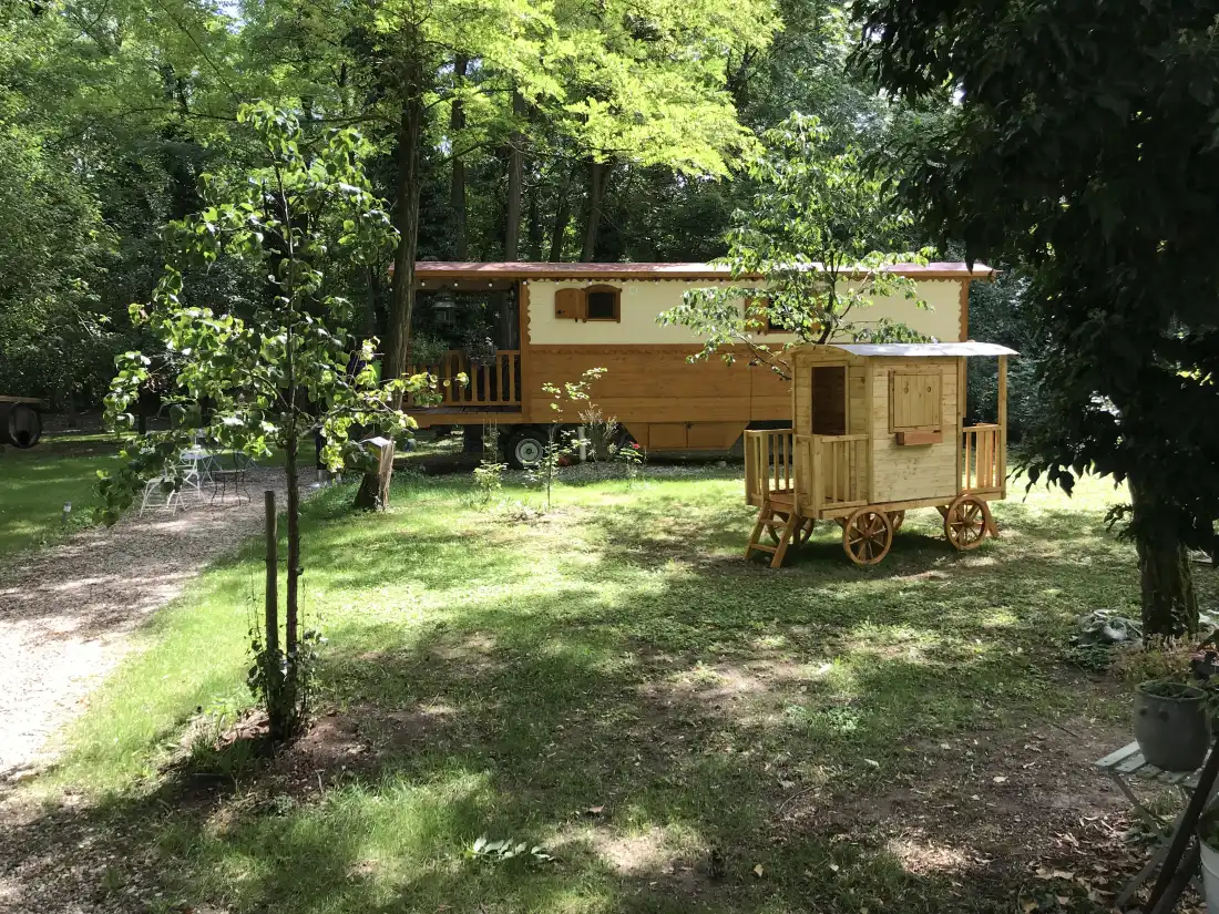 The wooden roulotte under the garden trees, in summer